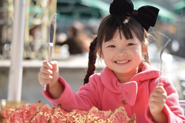 お肉を前にして笑顔がかわいい小さな女の子の写真